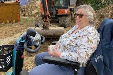 Pensioner, 76, in mobility scooter faces down diggers in ‘tense’ stand-off with builders over 20ft wall outside her home