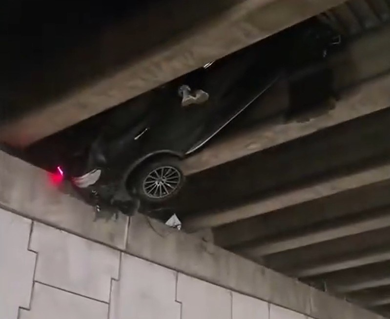 Shocking moment driver’s feet dangle from car wedged in motorway bridge after losing control of vehicle